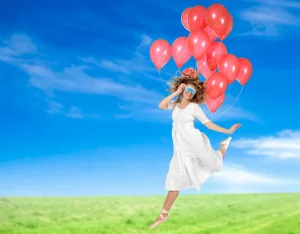 Une femme porte des lunettes de luminothérapie Psio, elle dégage de la légèreté car elle est comme suspendue par une grappe de ballon